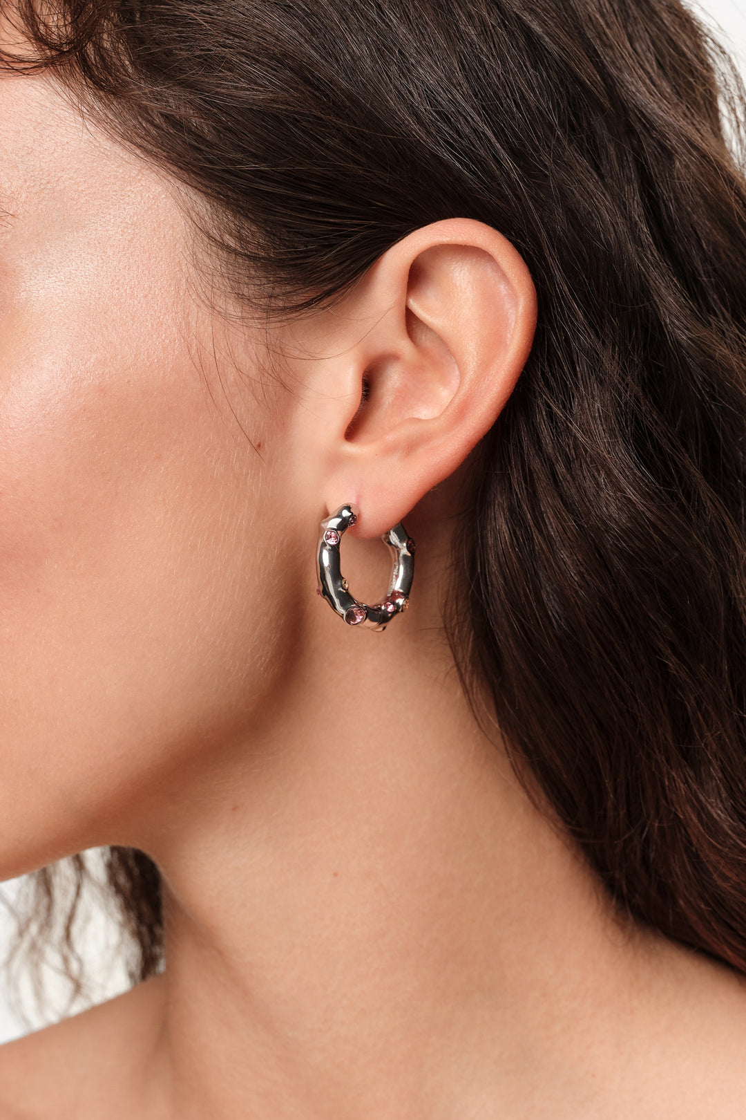 Silver textured metal hoop earrings with pink crystals