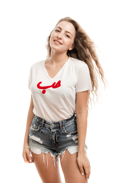 young adult female wearing white t-shirt with Hobb written in arabic حب and in red velvet in the center of the t-shirt along with blue jeans shorts