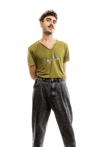 young adult male wearing olive green t-shirt with hobb written in arabic حب and in army pattern in the center of the t-shirt along with black jeans